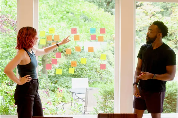 Two marketers working on strategic plan with post-it-notes on a window.